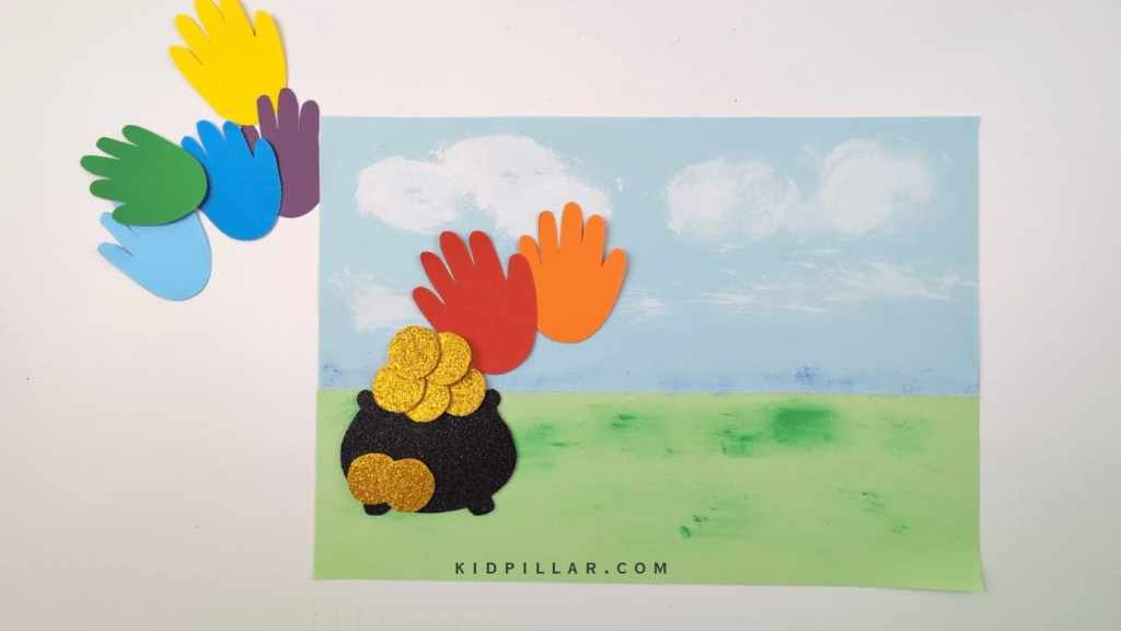 Paste handprints in VIBGYOR sequence to make the Rainbow pot of gold handprint craft for toddlers